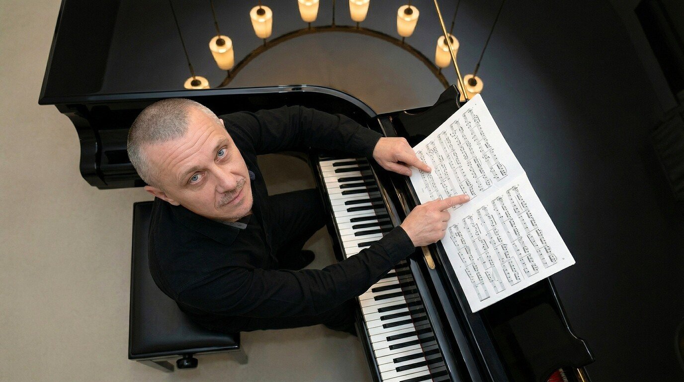 Top-down view of a musician playing grand piano with sheet music and candles.